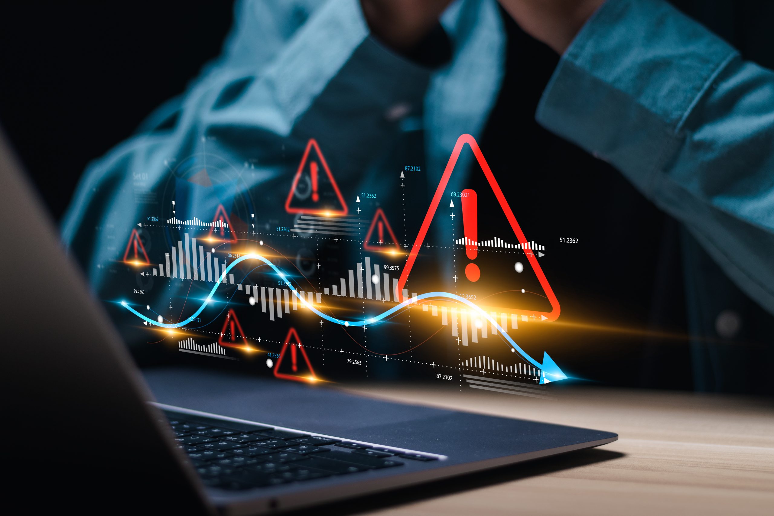 Laptop with digital warning icons and fluctuating financial data charts, symbolizing dirty data risks for CFOs.