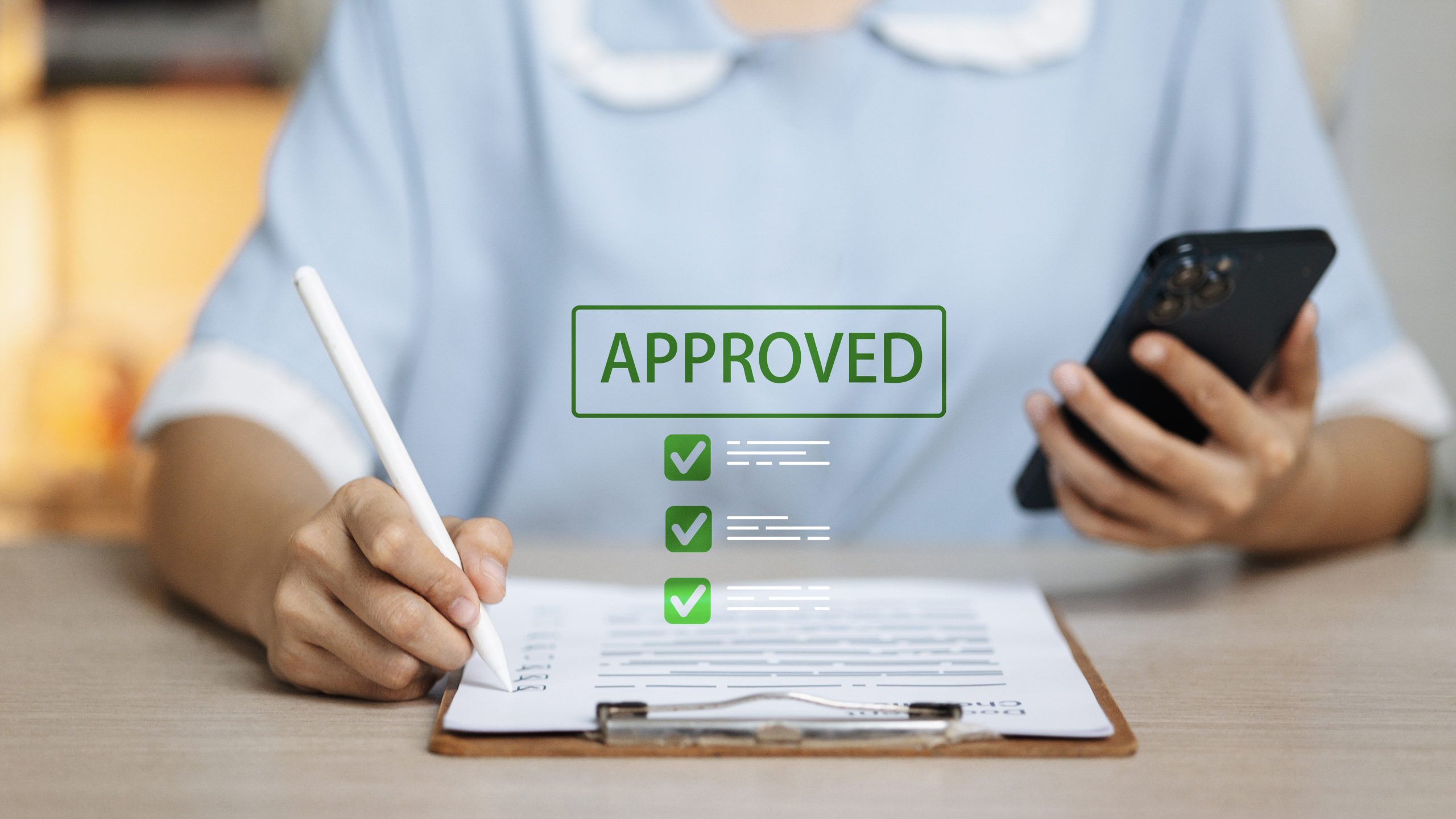 A person reviews a clipboard while a digital “Approved” confirmation graphic appears above the form.